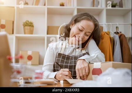 Asian dressmaker taking an order by phone. Seamstress writes down the ...
