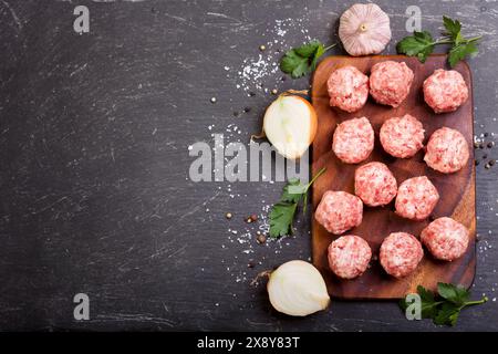 fresh raw meatballs with vegetables on dark table Stock Photo