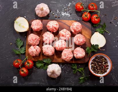 fresh raw meatballs with vegetables on dark table Stock Photo