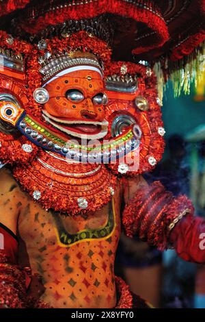 India, Kerala, Kannur, Theyyam ceremony. Beautifully dressed and with their faces painted entirely red, artists can take the form of multiple local de Stock Photo