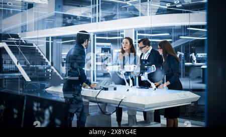 Robotics Engineer, Project Manager and Machinery Operators Collaborate on a Robot Canine Project, Standing with Laptop Computer in Scientific Technology Lab. Young Team Developing an AI Robotic Dog. Stock Photo