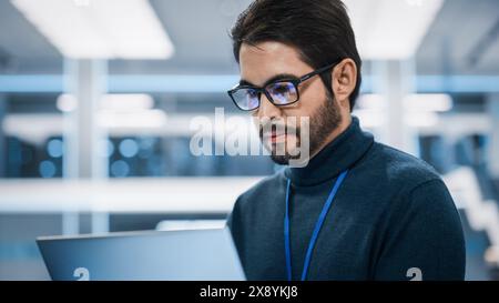 Portrait of a Professional Hispanic Man Using Laptop at Work in Research and Development Agency. Young Multiethnic Male Engineer, Developer or Scientist Working in Development Technology Office. Stock Photo