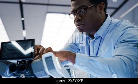 Robotics Engineer Working with Screwdriver, Collaborating on a Mobile Robot Animal Project. Close Up of a Black Man Screwing In a Circuit Board. Young Team Developing an AI Robotic Dog. Stock Photo