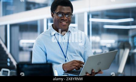 Portrait of a Handsome African Man Wearing Smart Corporate Wear and Glasses, Looking at Camera and Smiling. Businessman, Information Technology Manager, Developer, Robotics Engineering Specialist. Stock Photo