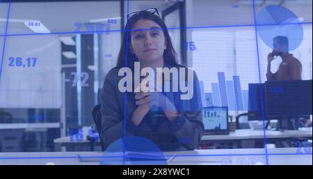 Image of statistical data and graphs, caucasian woman looking at camera and discussing in office Stock Photo