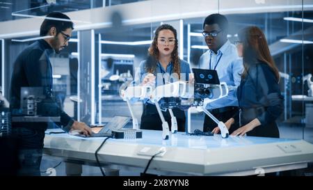 Robotics Engineers, Project Manager and Machinery Operators Collaborate on a Mobile Robot Animal Project, Using Computers and Connecting Circuit Board. Young Team Developing an AI Robotic Dog. Stock Photo