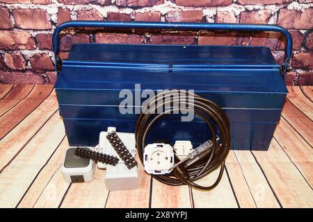 toolbox with switch, socket, light bulb and power cable, symbol image for electricians Stock Photo