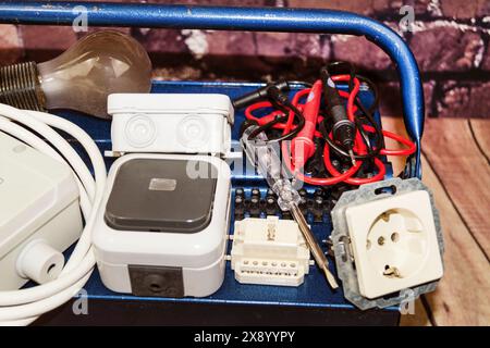 toolbox with switch, socket, light bulb, voltage tester and power cable, symbol image for electricians Stock Photo