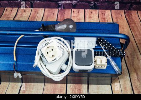 toolbox with switch, socket, light bulb and power cable, symbol image for electricians Stock Photo