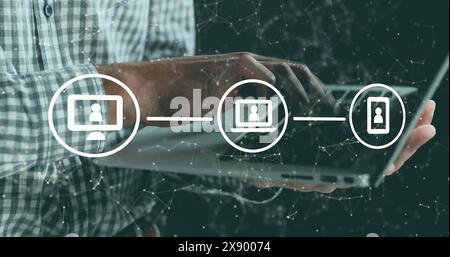 A man is using a digital tablet while standing against a black background Stock Photo