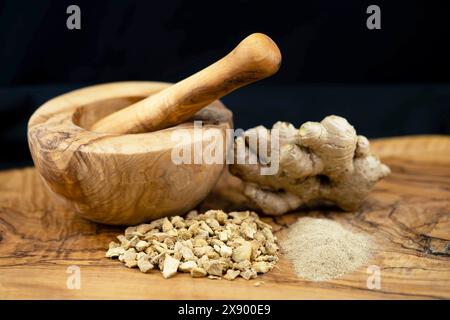 Ginger tubers, crushed in a wooden bowl, with mortar and ginger powder Stock Photo