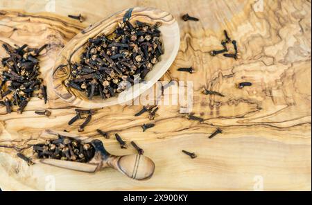 Clove (Syzygium aromaticum), Dried cloves on a wooden bowl and wooden scoop Stock Photo