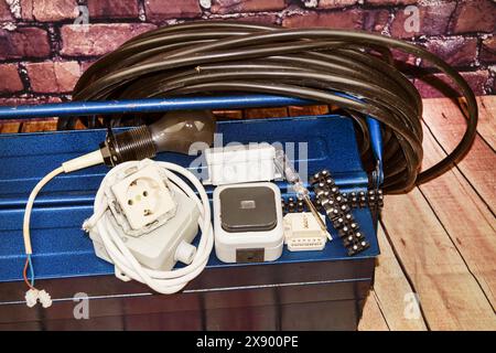 toolbox with switch, socket, light bulb and power cable, symbol image for electricians Stock Photo