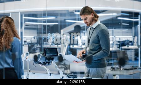 Young System Administrator Checking Online Internet Connectivity with a Prototype AI Robot Machine. Team Building Next Generation Mobile Robot Helper with Advanced Mobility, Dexterity and Intelligence Stock Photo