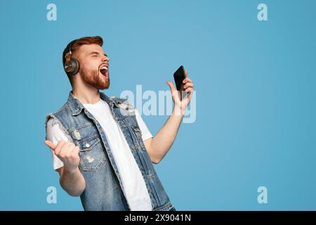 Cool young man singing in headphones on background Stock Photo