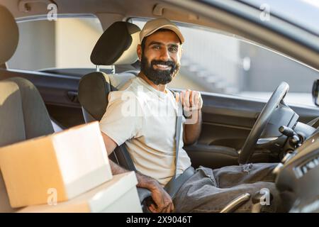 Driver Smiling While Fastening Seatbelt in Car With Packages Stock Photo