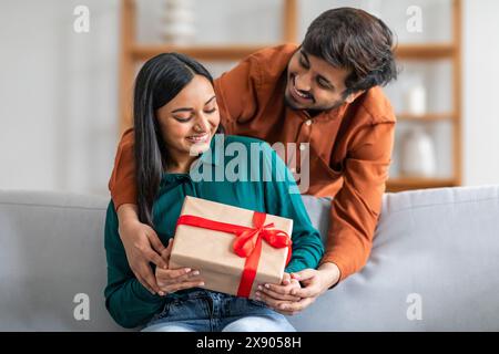 Man Giving Gift to Woman on Couch Stock Photo