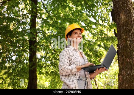 Forester in hard hat with laptop working in forest Stock Photo