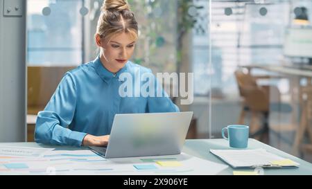 Portrait of a Smiling White Female Working on a Creative Job Position in an Advertising Company Using Laptop Computer. Happy Manager Interacting with Colleagues, Writing a Marketing Plan Stock Photo