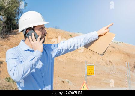 architect working on a construction with plans and using mobile phone Stock Photo