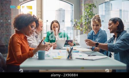 Modern Multi-Ethnic Architectural Agency Office Meeting. Group of Professional Architects, Designers Discussing Design Sustainable, Energy Efficient Housing Project, Using Laptop Tablet, Statistics Stock Photo
