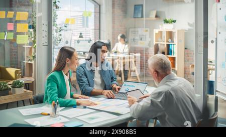 Multiethnic Group of People Use Tablet, Laptop and Statistics Data to Discuss Work in Office Conference Meeting Room. Diverse Colleagues Solving Problems, Teamwork leads to Great Results Stock Photo