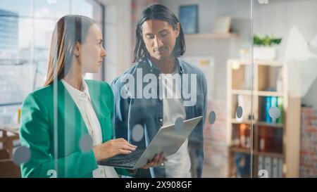 Businesspeople in Modern Office: Business Meeting of Two Managers Using Laptop. Female CEO and Operations Director Talk, Discuss Corporate Strategy, Implementing Marketing and Financial Plans Stock Photo