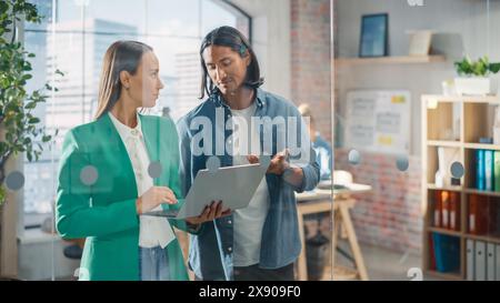 Businesspeople in Modern Office: Business Meeting of Two Managers Using Laptop. Female CEO and Operations Director Talk, Discuss Corporate Strategy, Implementing Marketing and Financial Plans Stock Photo
