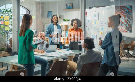 Portrait of a Beautiful Black Woman in Smart Casual Clothes Doing a Presentation in a Meeting Room for her Colleagues. Female Manager Answering Questions and Writing on White Board Stock Photo