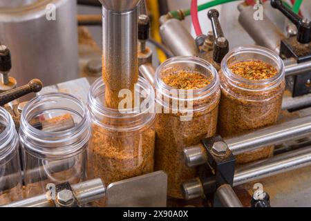 Jars being filled with spices on automated assembly line, Pennsylvania, USA Stock Photo