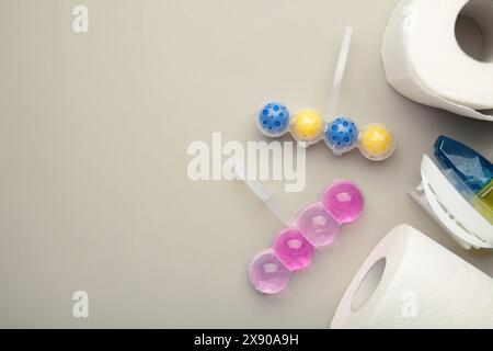 Toilet balls and toilet paper on grey background. Clean the toilet bowl with cleaning and refreshing balls. Space for text Stock Photo