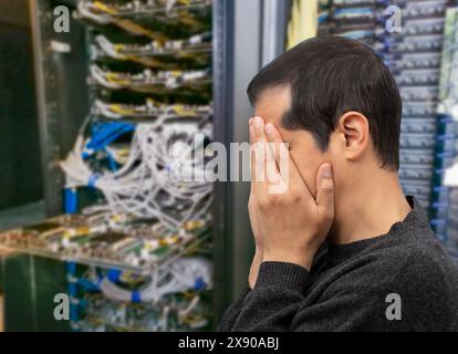 Profile shot of an IT technician having difficulty repairing a computer in a data center of AI. Stock Photo