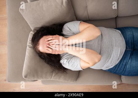 Top view of sad woman complaining in the night lying on a couch in the living room at home Stock Photo