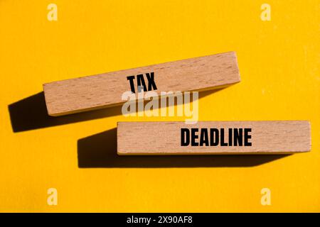 Tax deadline words written on wooden blocks with yellow background. Conceptual tax deadline symbol. Copy space. Stock Photo