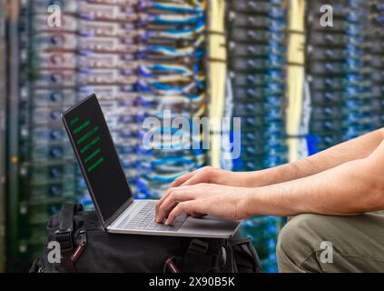 Server room, network and laptop with businessman in data center for engineering, technology,AI and cloud computing. Cybersecurity, internet and mining Stock Photo