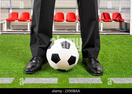 Close up of coach standing next to chalk line on soccer field with ball classic Stock Photo