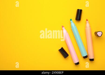Open markers and space for text on yellow background. Pink, blue and orange highlighters Stock Photo