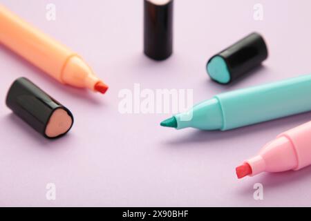 Open markers and space for text on purple background. Pink, blue and orange highlighters Stock Photo