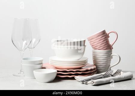 Beautiful ceramic dishware, cups, glasses and cutlery on light grey table Stock Photo