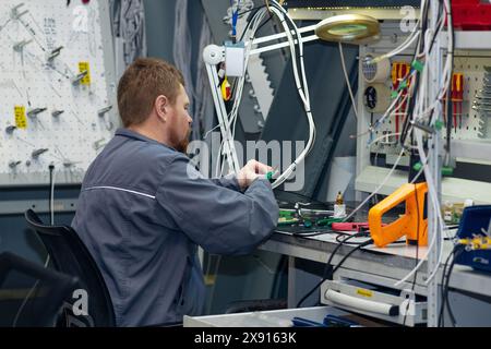 Perm, Russia - May 23, 2024: worker assembling electrical equipment in a workshop Stock Photo