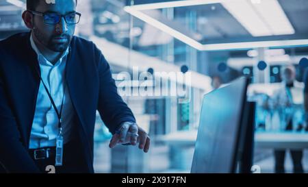 Portrait of Industrial Engineers Discussing Work, Talk and Use Desktop Computer in Turbine Manufacturing Facility. Specialists Researching and Developing Innovative Jet Engine in 3D CAD Software. Stock Photo