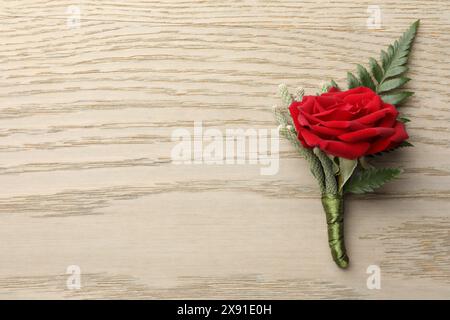 One stylish red boutonniere on light wooden table, top view. Space for text Stock Photo