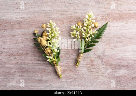 Small stylish boutonnieres on light wooden table, top view Stock Photo