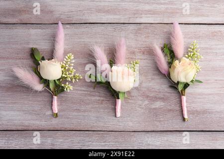 Many small stylish boutonnieres on light wooden table, flat lay Stock Photo