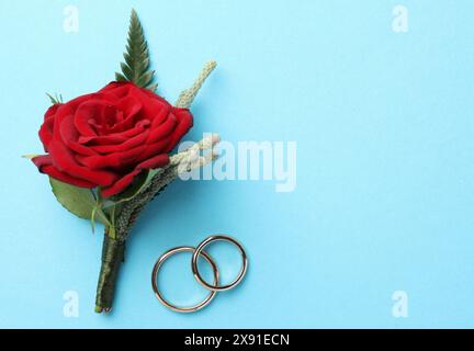 Small stylish boutonniere and rings on light blue background, top view. Space for text Stock Photo