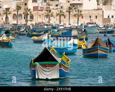 Colourful fishing boats in the harbour, surrounded by palm trees and coastal houses, colourful boats in a historic harbour on the Mediterranean Stock Photo