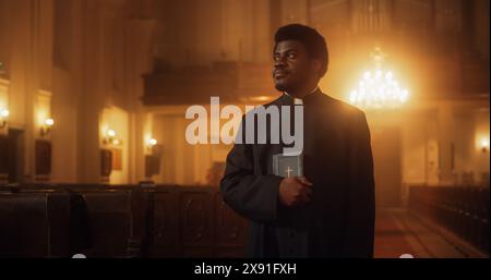 Portrait of a Young Black Priest Holding the Holy Bible in His Hand. A Servant of God Helping Lost Souls Find the Path of Righteousness through Faith. A Symbol Of Christianity, God's Love And Grace Stock Photo