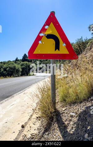 Bullet holes in road sign is target for target practice of bullets shot through, Crete, Greece Stock Photo