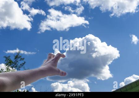 Child's hand arranges clouds in sky. concept of cloud computing Stock Photo