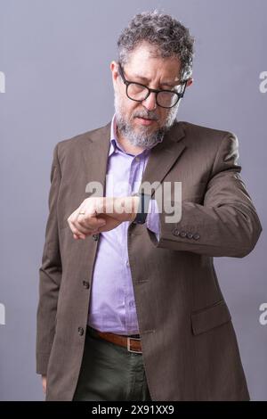 Professional businessman wearing a suit and glasses, checking his smartwatch. Corporate time management, punctuality, and professionalism Stock Photo